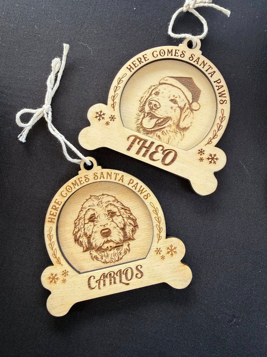 Two wooden Christmas ornaments with engraved dog portraits and names on a black background.